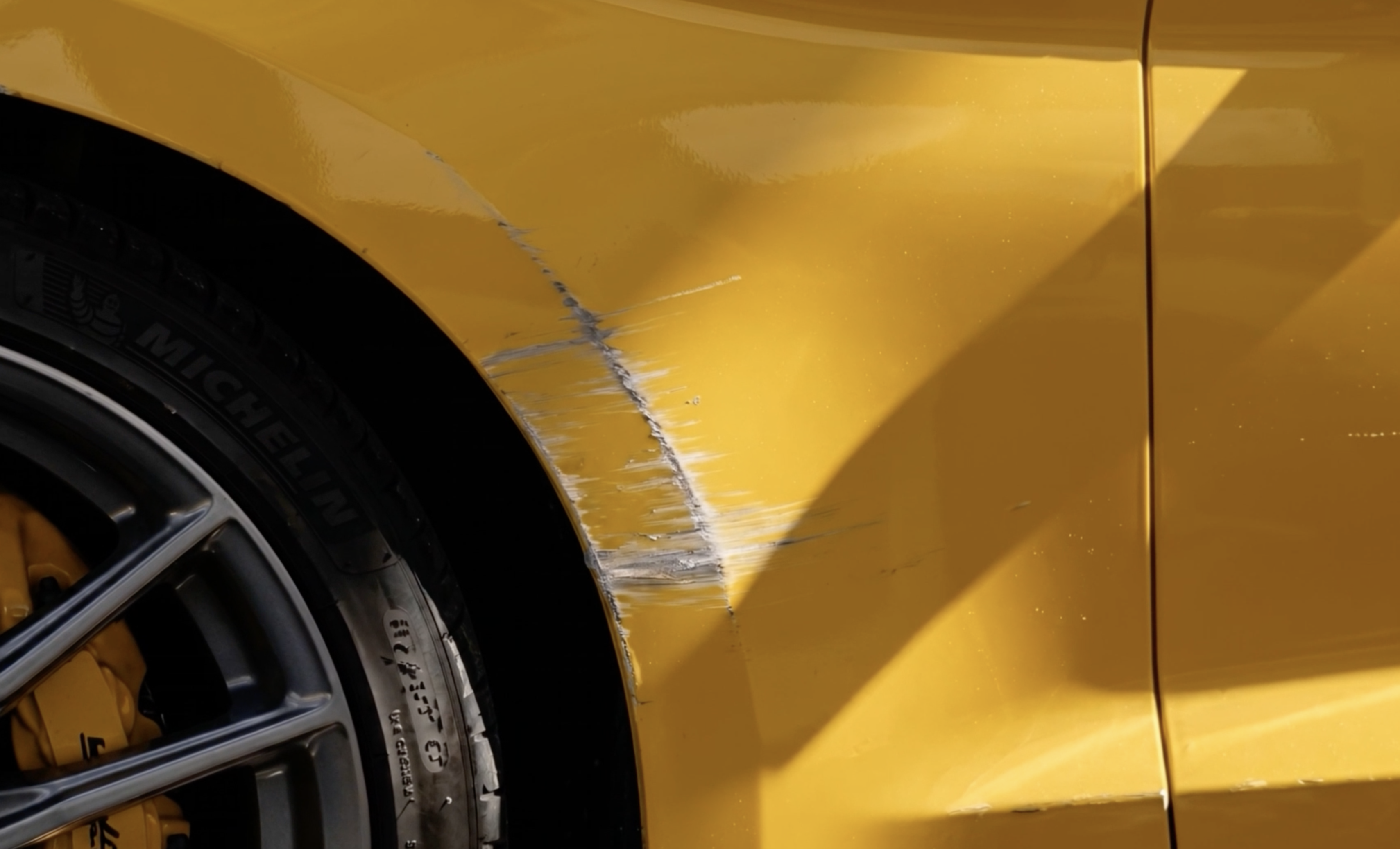 A kerb scrape on a yellow fender taken by the protective film, not the paint